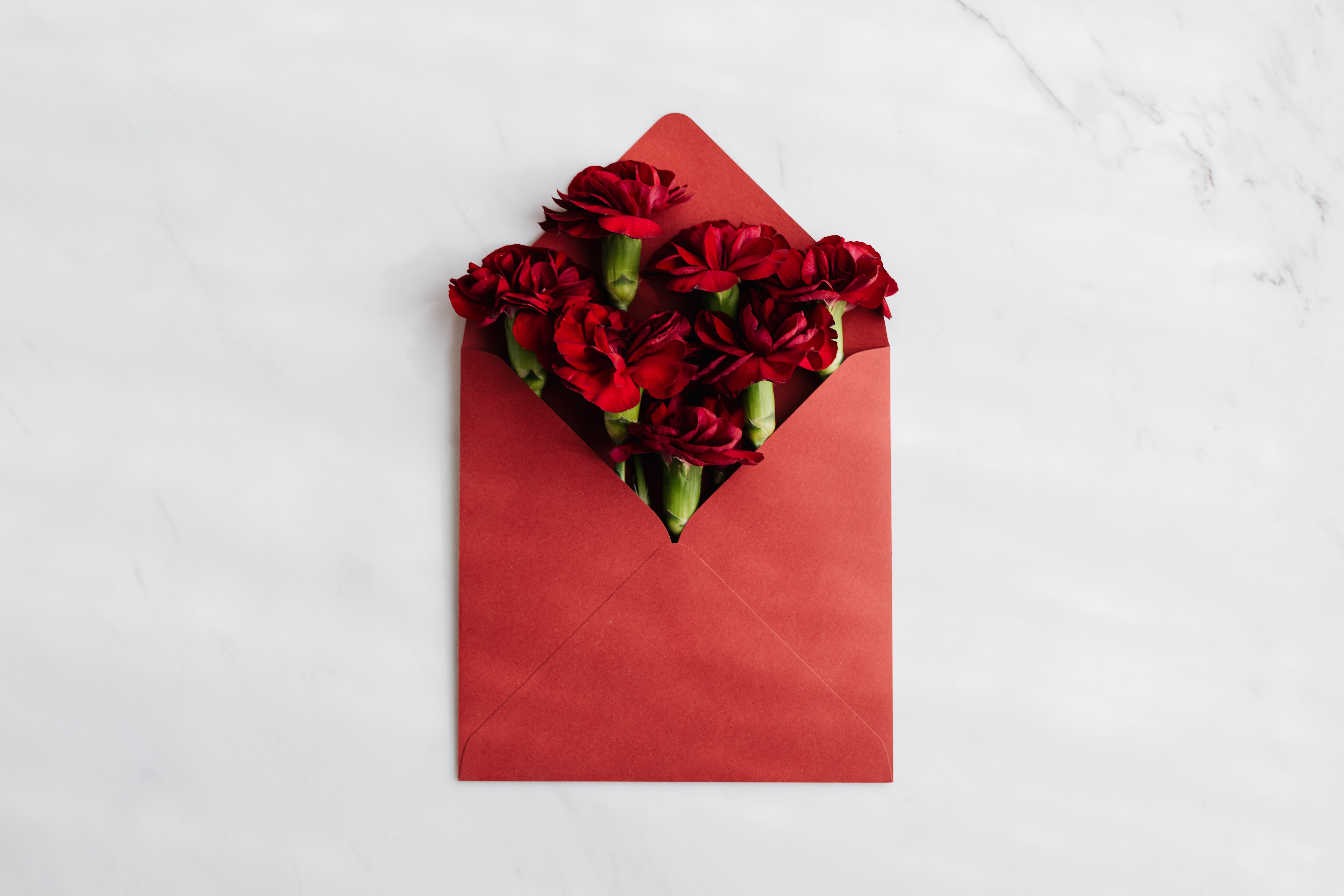 A red envelope with red flowers coming out of it.