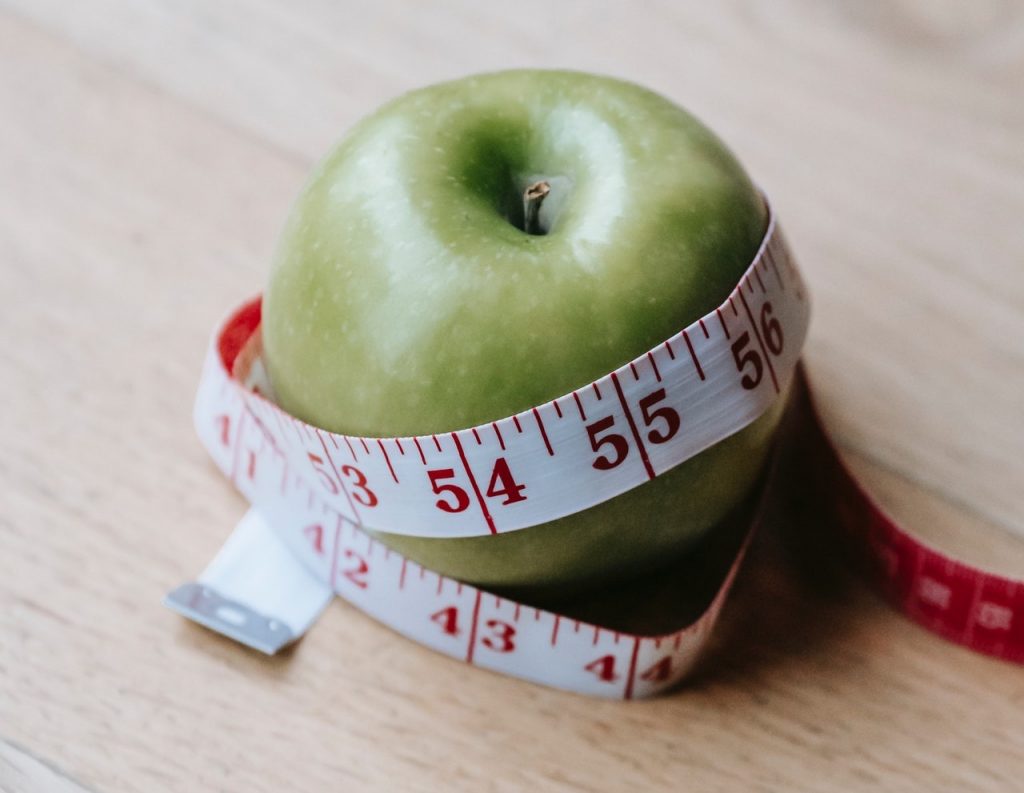 Green apple with measuring tape wrapped around it